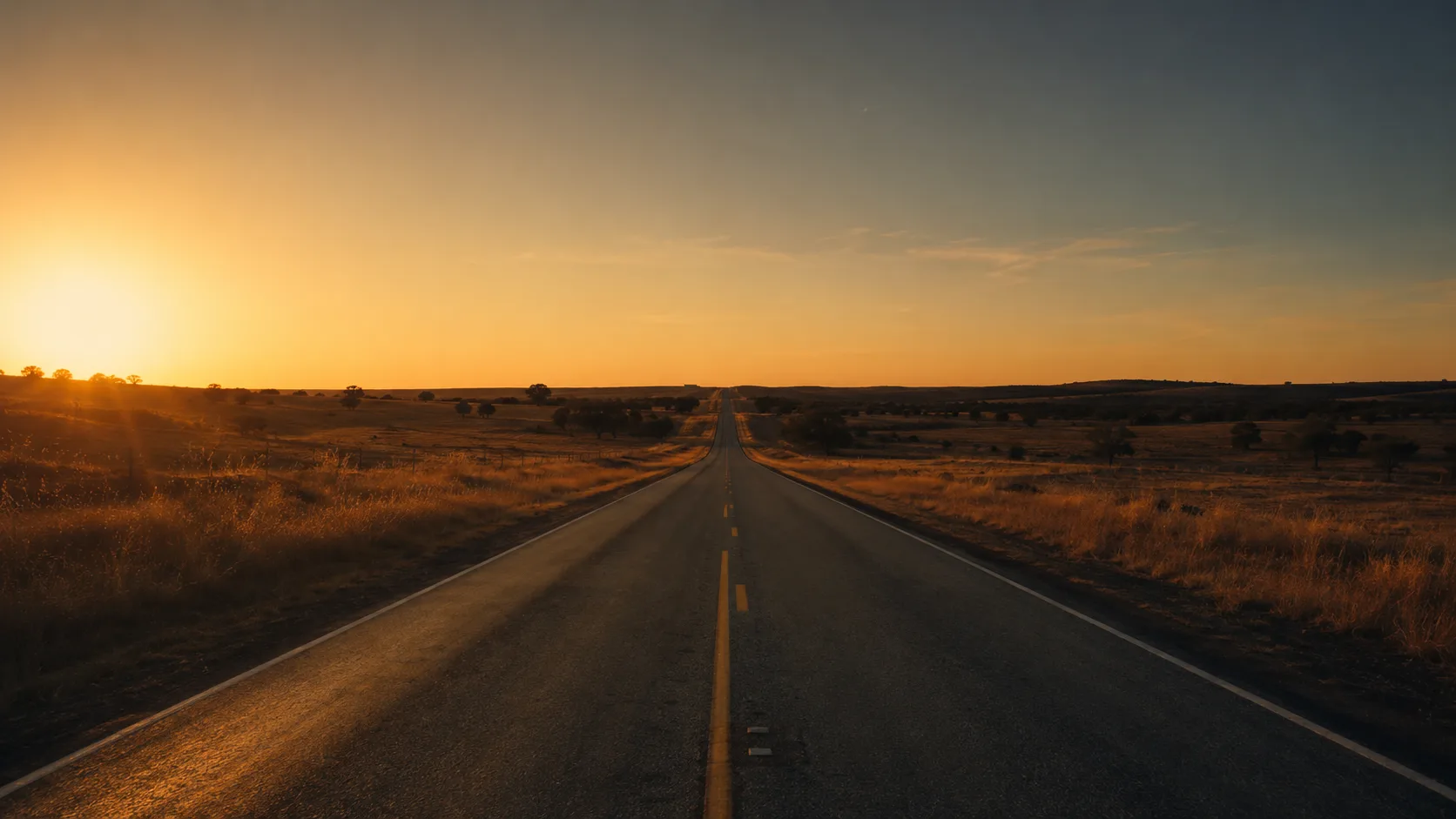 An empty Texas two-lane highway at dusk, the kind of road where unseen gravel waits in a blind corner.